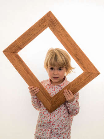 a child holds a frame in her hand and looks through.の写真素材