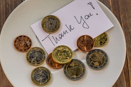 a plate of coins for a tip or fee toilets. in englishの写真素材