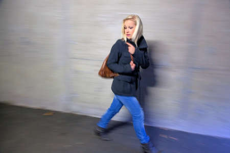 a young woman in an underpass for pedestrians is afraid of harassment and crimeの写真素材