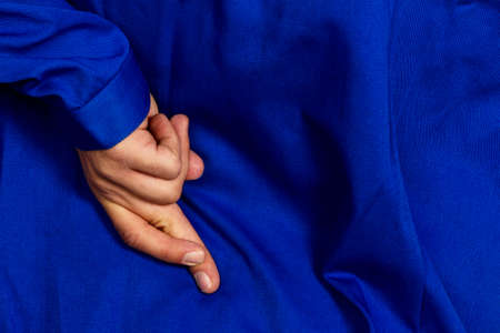 a craftsman crossed fingers behind his back. falsehood and untruth in the commercial.の写真素材