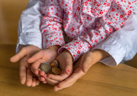 children hold coins of money in their hands. symbolfoto learn for saving and handling money.の写真素材