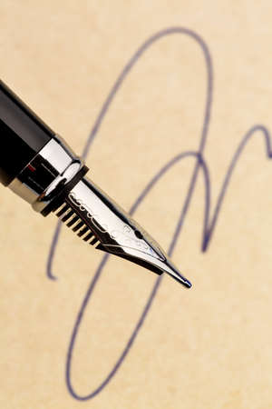a signature and a fountain pen on yellow paper. symbol photo for contract, testament and graphologyの写真素材