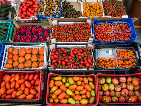 in a small italian town, a fruit and vegetable store. many different types of tomatoの写真素材