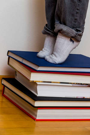 child standing on a pile of booksの写真素材