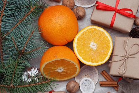 Gift box in craft paper with bow, pinecones, oranges fruit, cinnamon, nuts on wooden backgroundの写真素材