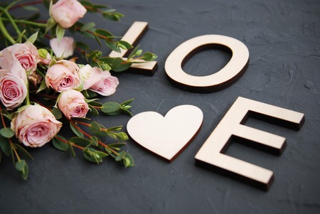 Love letters and pink rose flowers wooden background, top view, vintage toned imageの写真素材