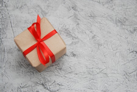 Rustic gift box craft paper and red bow on gray backgroundの写真素材