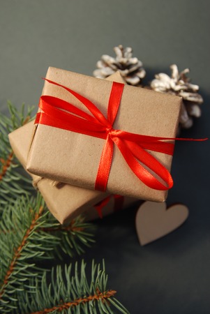 Gift box or mail parcel, post delivery wrapped with kraft paper and twine rope and decorated with red bow isolated on white background. Craft present for christmas, valentine or other holidayの写真素材