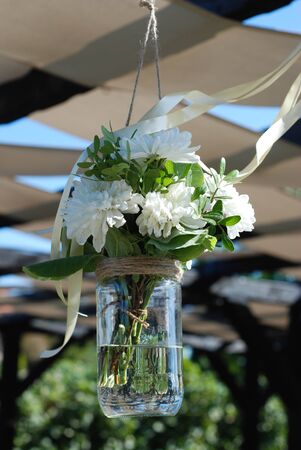 White roses in a glass vase hung in a wedding partyの写真素材