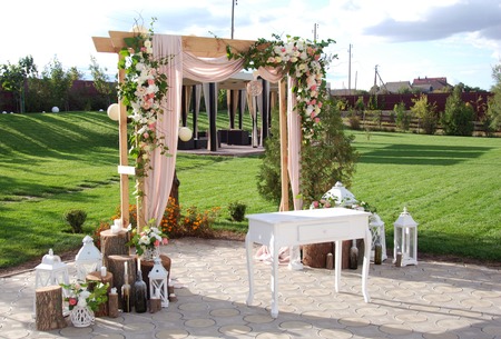 Arch for the Wedding ceremony, decorated with cloth flowers and greenery, is in a pine forestの写真素材