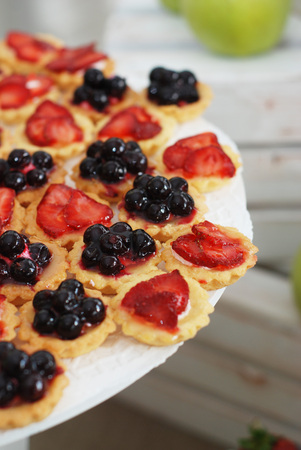 Fruit and berry tartlets dessert. Beautiful delicious tarts, bright, colorful pastry cakes sweets with fresh raspberries, figs, strawberry. French Bakery pattern.の写真素材