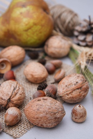 Autumn composition with nuts, pears and dry leaves on rustic backgroundの写真素材