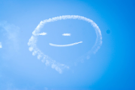 Jet airliner flying at high altitude drawing smile faceの写真素材