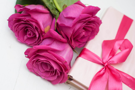 Bouquet of beautiful pink roses next to a pink gift with a happy mothers day card on white background close upの写真素材