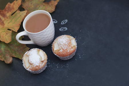 Chalkboard and coffee cup with muffins on a blackboard with maple yellow leavesの写真素材