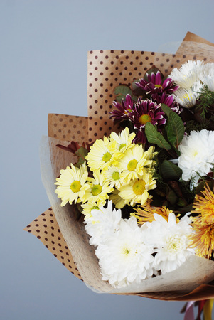 Bouquet in kraft paper. A simple bouquet of flowers and greens on gray backgroundの写真素材