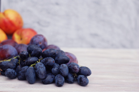 Blue grapes and peaches on rustic gray background. Autumn fruits.の写真素材