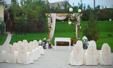 Beautiful summer wedding ceremony outdoors. Decorated chairs. Wedding arch white and pink flowers on a green background.の写真素材