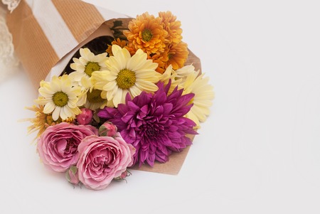 Bouquet of autumn chrysanthemum flowers in brown paper on white backgroundの写真素材