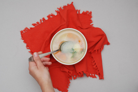 Hand holding spoon and bowl of soupの写真素材