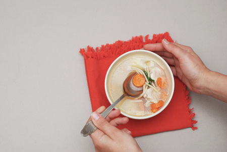Hand holding a bowl with soup withの写真素材