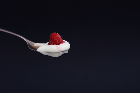 Spoon of natural yogurt with raspberry fruitの写真素材