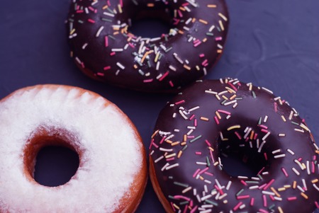 Three donuts with chocolate with black tableの写真素材