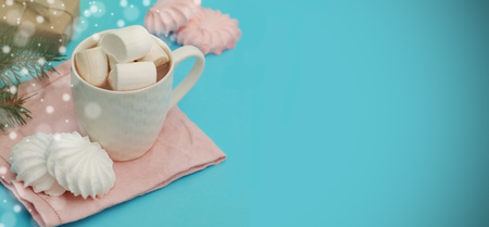 Hot Chocolate or Cocoa Cup with Marshmallows and Fir Branches and Pink Napkin isolated on Blue background with Text Space.の写真素材