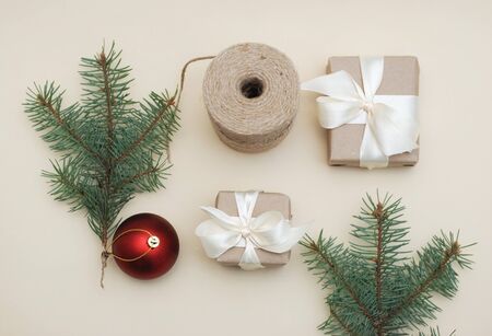 Christmas Concept. Gift wrapped in paper and tied with White ribbon lies near the ChristmasFir Branch and Red Globeの写真素材