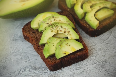 Sliced Avocado on Toast Bread with Spices on a skratched Gray Board.の写真素材