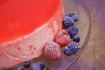 Red mirror glazed cake with berries close up on Wooden Backgroundの写真素材