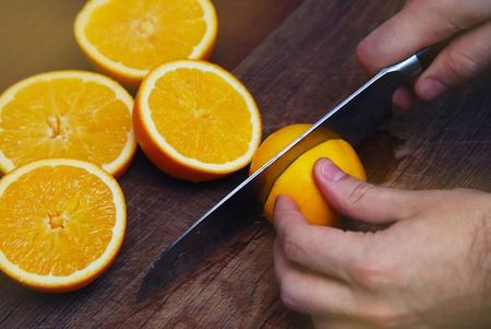 Mens hands cutting fresh orange on kitchen. Food Photographyの写真素材
