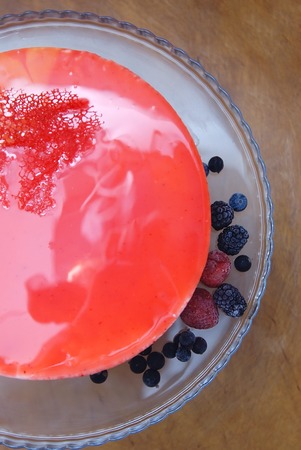 Modern mousse cake with red glaze and mixed berriesの写真素材