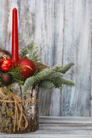 Modern arrangement with candles on wooden table with red balls or globes and fir branchesの写真素材