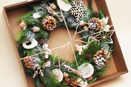 Rustic Christmas wreath with green fir branches, pinecones, natural elements. Wraped in craft box, gift box isolatedの写真素材