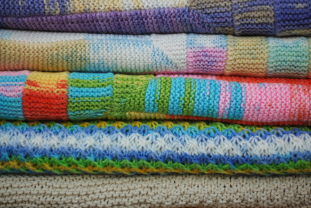 Stack of various colorful knitted blankets. Winter style. Isolated on white backgroundの写真素材