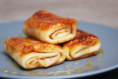 Bakery. Traditional Russian Pancakes. International Pancake Day on 28 February. Roled delicious pancakes with cheese with honey on gray plateの写真素材