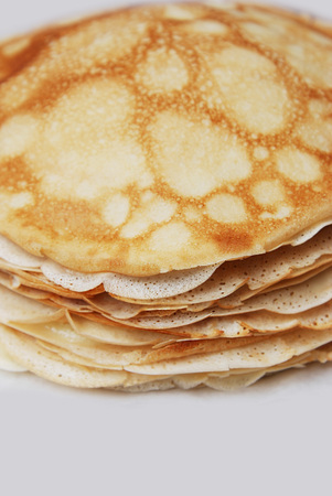 Stack of English pancakes on a round white plate on a black background. Pancake Day in Britain. Appetizing russian pancakes for Maslenitsa carnival Shrovetide . Close up. Vertical image.の写真素材