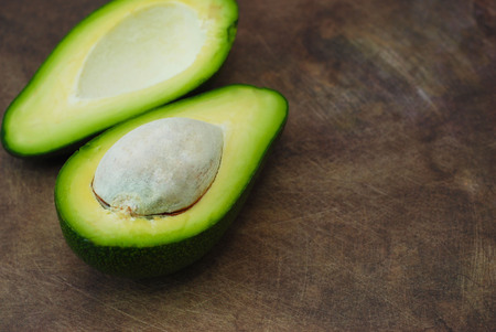Fresh Avocado sliced over vintage wooden background close up. Ripe green avocado fruit on wood board.の写真素材