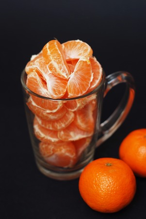 Peeled Tangerines mandarins in glass on dark background. Healthy food concept, vitamines and juice. Vertical Image.の写真素材