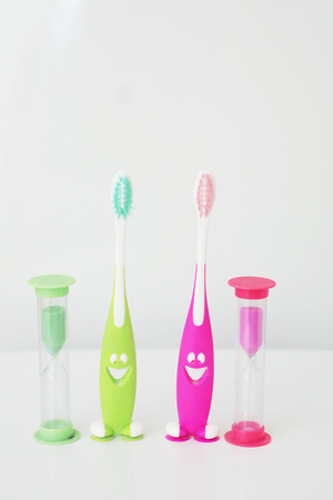 A photo of the hourglasses and two toothbrushes. Time to clean the teeth. Dental care, personal childrens hygiene concept photo.の写真素材