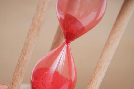 Hourglass as Time Concept and Running out of time. Sandglass. Neutral Ivory Background. Vertical Image. Timmig. Ivory Neutral Background.の写真素材