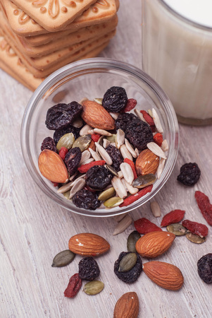 Nuts and Dried Fruits Mix on Rustic Wooden Background. Glass of Milk and Biscuits.の写真素材