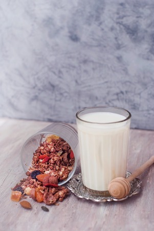 Glass of Milk and Granola bowl. Healthy Nuts and Dried Fruits on Rustic Wooden Background.の写真素材