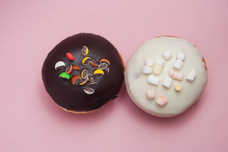 Top view Doughnuts with Chocolate and White Icing on Pastel Pink Background. Sweet Dessert Donutsの写真素材