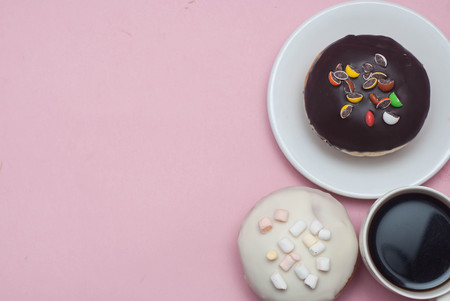 Doughnuts with Icing and cup of Coffee, on Pastel Pink Background. Sweet Dessert Donutsの写真素材