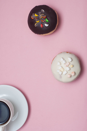 Top view Doughnuts with Icing and cup of Coffee, on Pastel Pink Background. Sweet Dessert Donutsの写真素材
