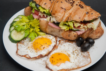 Sandwich Croissant with Cheese, Tomato, Cucumber and Fried Eggs. Breakfast with Eggsの写真素材