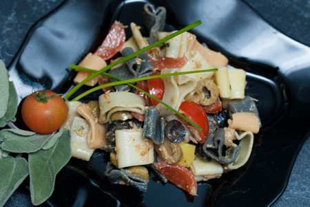 Colorful Pasta Heart-Shaped with Sauce, olivevs, Tomatoes in Black Plate.の写真素材