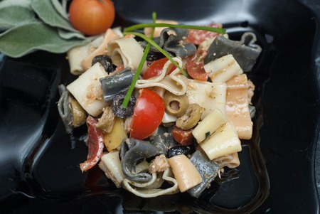 Heart-Shaped Colorful Pasta with Sauce, olivevs, Tomatoes in Black Plate.の写真素材